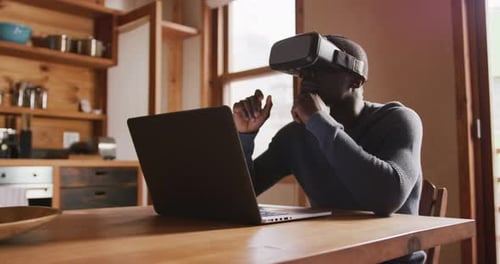 Man Wearing VR Headset Using Laptop at Home