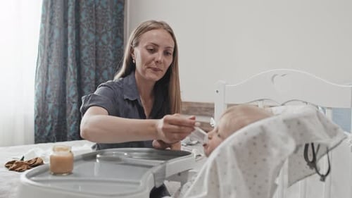 Woman Feeding Baby Food at Home