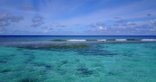 Daytime above tourism shot of a white sandy paradise beach and blue ocean background in colorful 4K