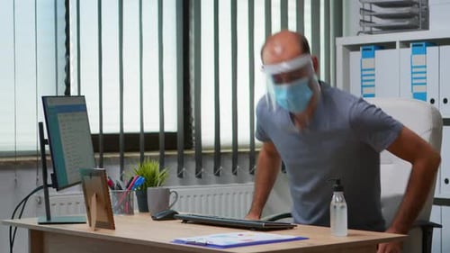 Man Using Computer with Face Shield and Mask