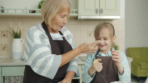 Abuela y nieta divirtiéndose en la cocina cocinando riendo haciendo galletas