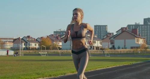 Woman Running at a Stadium in Sunny Day.