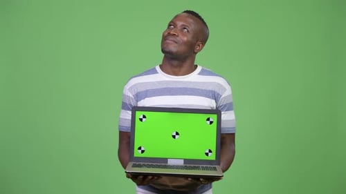 Smiling Young Adult Holding Laptop with Green Screen