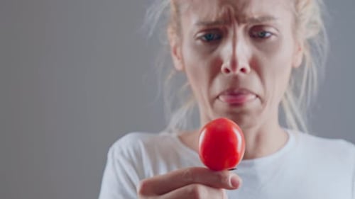 Young Woman Holding Tomato Tasting Something Sour
