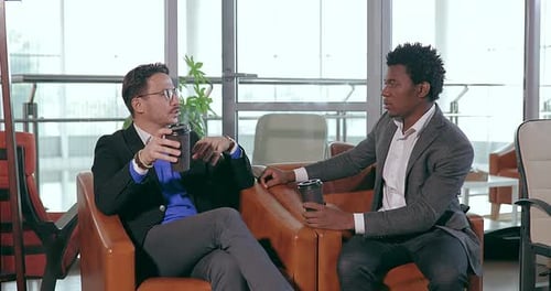 Businesspeople European and African Talking While Sitting in Chair in Office