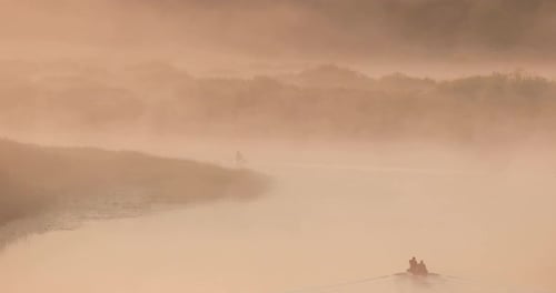 Calm Lake River And Man Fishing From Old Wooden Rowing Fishing Boat At Beautiful Misty Sunrise In