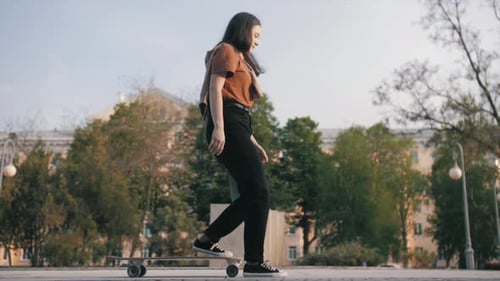 Happy girl is skateboarding at summer holidays and weekend, young woman is riding on skateboard, spo
