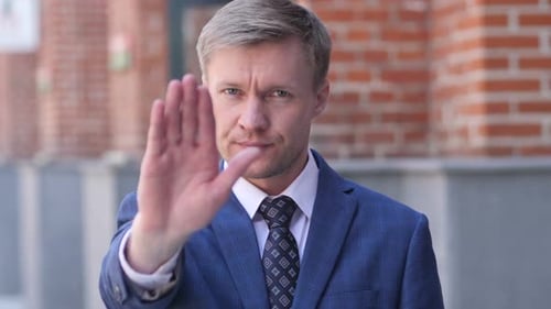Man in Suit Displays Stop Hand Gesture