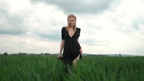 Girl In Black Dress Runs The Field. Romantic Image Of Blonde.