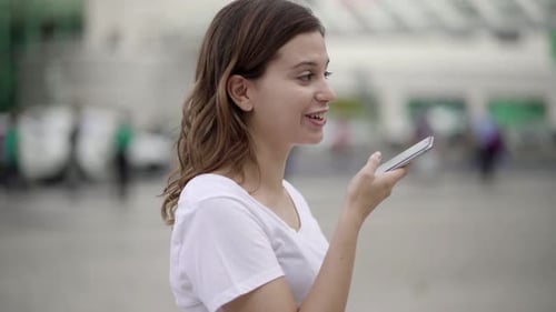 Young Woman Uses Voice Command on Phone in City