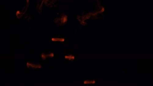 Abstract Footage of Red Ink Swirling in Darkness