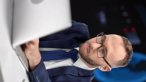 VERTICAL VIDEO POV Male Boss in Tie Suit Working on Laptop at Hi Tech Office Infographics Screen
