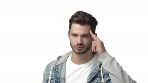 Frecher und selbstbewusster attraktiver Mann mit Bart, der Sie in Zeitlupe grüßt, wenn Sie den Tempel mit den Finger berühren