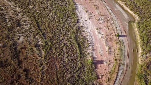 Flying aerial view of winding river flowing through the desert