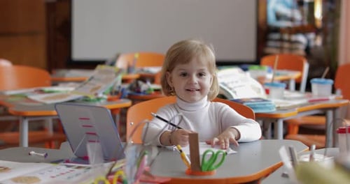 Child Drawing at Desk in Classroom