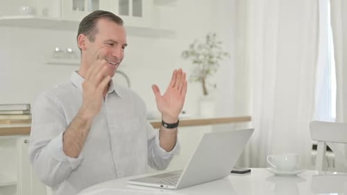 Man works on laptop at kitchen table