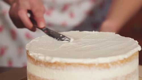 Rotierender Kuchen mit Buttercreme, Frauenhand berühren sich mit dem Messer