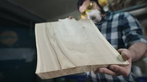 Woodworker Inspecting Piece of Cut Wood