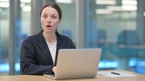 Businesswoman Using Laptop Looks Shocked in Office