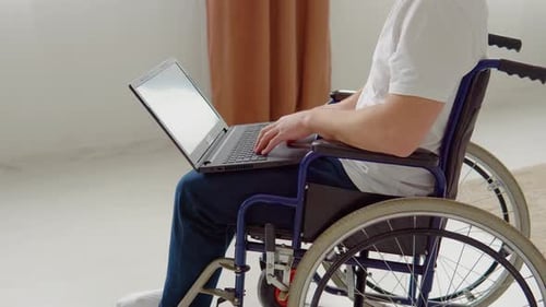 Man in Wheelchair Using Laptop Indoors