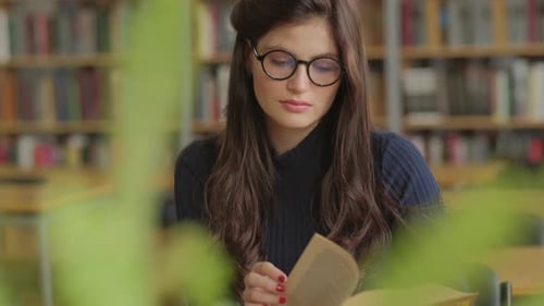 Young, Beautiful Woman Is Reading a Book in a Library. Student and Learning Concept.