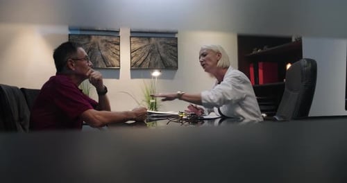 Slow Motion female doctor communicates bad health news to senior patient at clinic consultation.