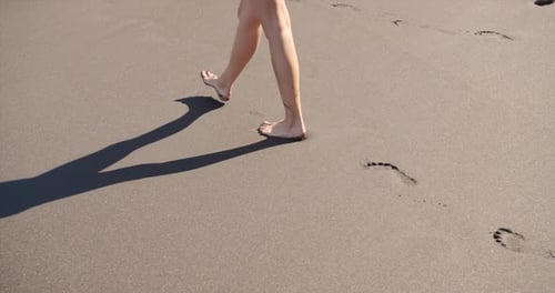 Woman Feet Walking Barefoot on Beach Leaving Footprints in Sand.
