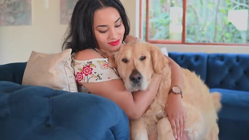 Woman Hugging Golden Retriever on Blue Couch Indoors