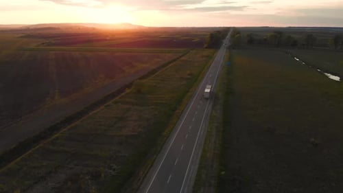Aerial shot: vehicles, trucks and cars driving by road.