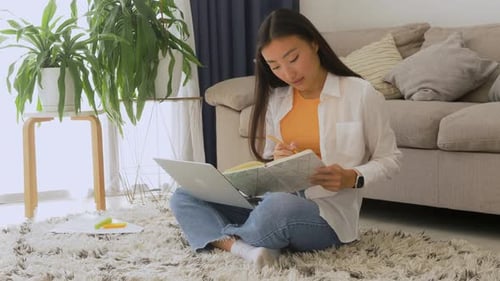 Woman Types on Laptop and Takes Notes