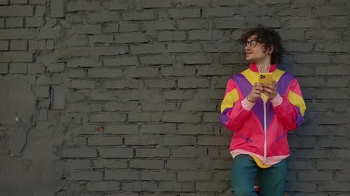 Young Adult Using Smartphone Against Urban Brick Wall