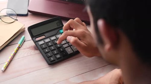 Vista posterior de una mano humana usando una calculadora