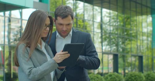 Business People Standing Near Business Center with Digital Tablet. Man and Woman Read News on Tablet