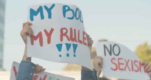 Gros plan de l'affiche My Body My Rules entre les mains d'une femme caucasienne. Une jeune organisation féministe méconnaissable