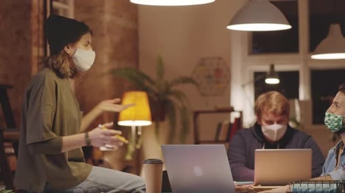 Male and Female Coworkers in Masks Discussing Job in Loft Office