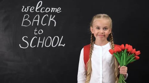 Cute Smiling Girl Holding Bunch of Tulips Near Chalkboard Welcome Back to School