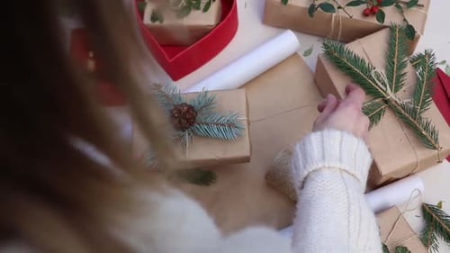 Woman wrapping Christmas presents with brown paper and twine