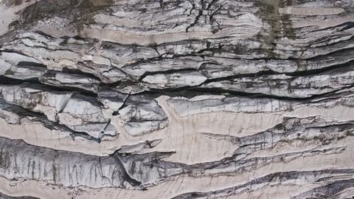 Gletscher bedeckt mit Steinfelsen, tiefen Rissen und kleinen Wasserfällen