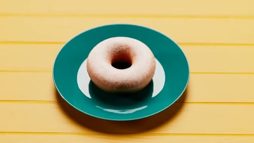 A plate with a delicious doughnut on a yellow table. Eating sweet dessert. 4K HD