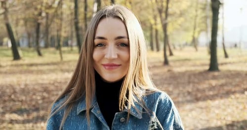 Portrait of Young Attractive Female Who Smiling and Looking at the Camera on Autumn Park. Cheerfully