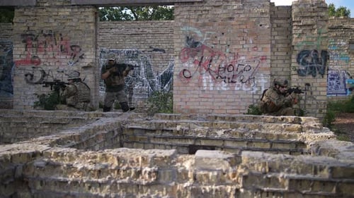 Camouflaged Soldiers Advancing Through Ruined Building
