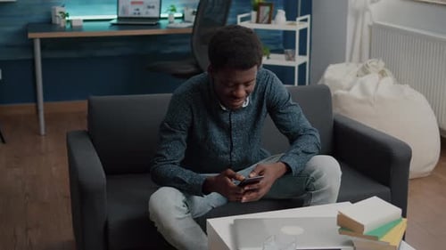 Young Adult Relaxing With Smartphone on Sofa