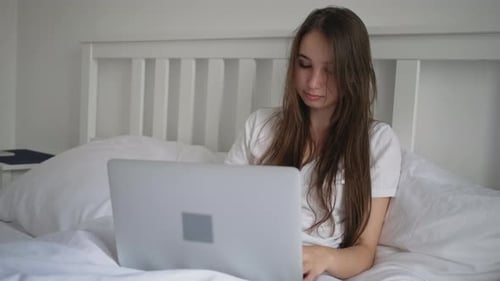 Woman in Bed Works on Laptop