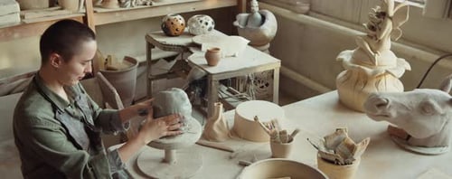 Woman Sculpting Face on Clay Head in Art Studio