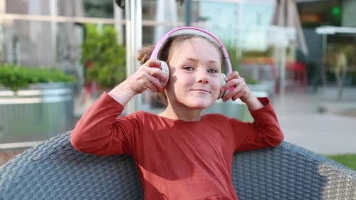 Girl Puts On Headphones While Sitting in Chair