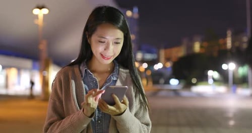 Woman Using Smartphone at Night in City
