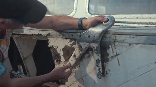 Adult repairing a boat on a sunny day