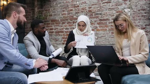 Muslim Businesswoman in Hijab Explaining to Her Multiracial Business Colleagues the Chart