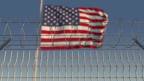 Barbed Wire Fence with Waving American Flag Background