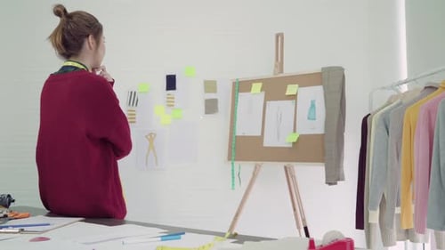 Asian female designer working with fabric sketches and drawing clothing design at the studio